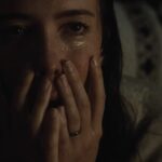 Rebecca Hall holds her hands over her mouth with tears in her eyes in the horror movie The Night House