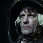 Thomas Jane wears a space suit and looks distressed in the film Warning