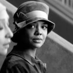 Tessa Thompson look intently at Ruth Negga who is slightly out of focus in a black and white photo from the movie Passing