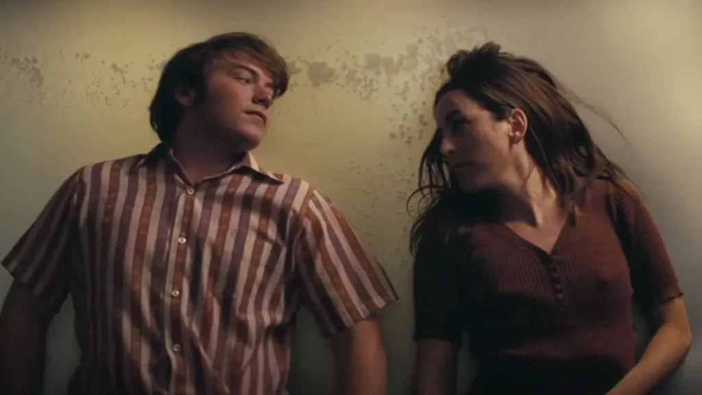 Cooper Hoffman and Alana Haim look at each other intently in the movie Licorice Pizza 