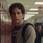 Ben Platt looks forlorn standing in front of a locker in the movie Dear Evan Hansen