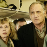 Mariya Belkina and Vladimir Friedman stand in a crowded ailse waiting to get off a plane in the film Golden Voices