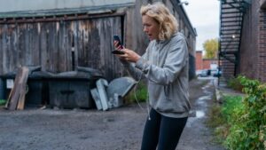 Naomi Watts stands looking frustrated at her phone in the movie The Desperate Hour