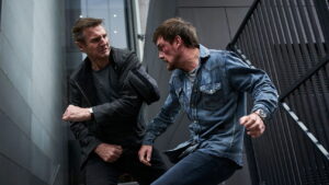 Liam Neeson punches a bloodied man in a stairwell in the movie Blacklight