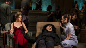 Viggo Mortensen lays on a chair in between Lea Seydoux and Kristen Stewart in the movie Crimes of the Future