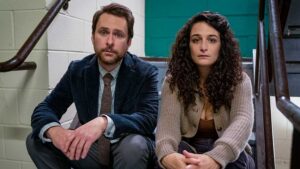 Charlie Day and Jenny Slate sit on stairs looking sad in the movie I Want You Back