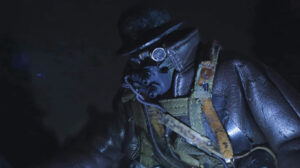 A character in a gas mask stands in light in the movie Mad God and helmet 