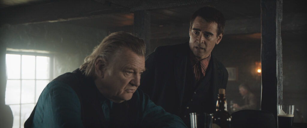 Colin Farrell leans over to talk to Brendan Gleeson at the bar in The Banshees of Inisherin