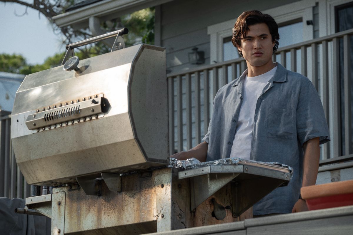 Charles Melton looks up while grilling in the movie May December.