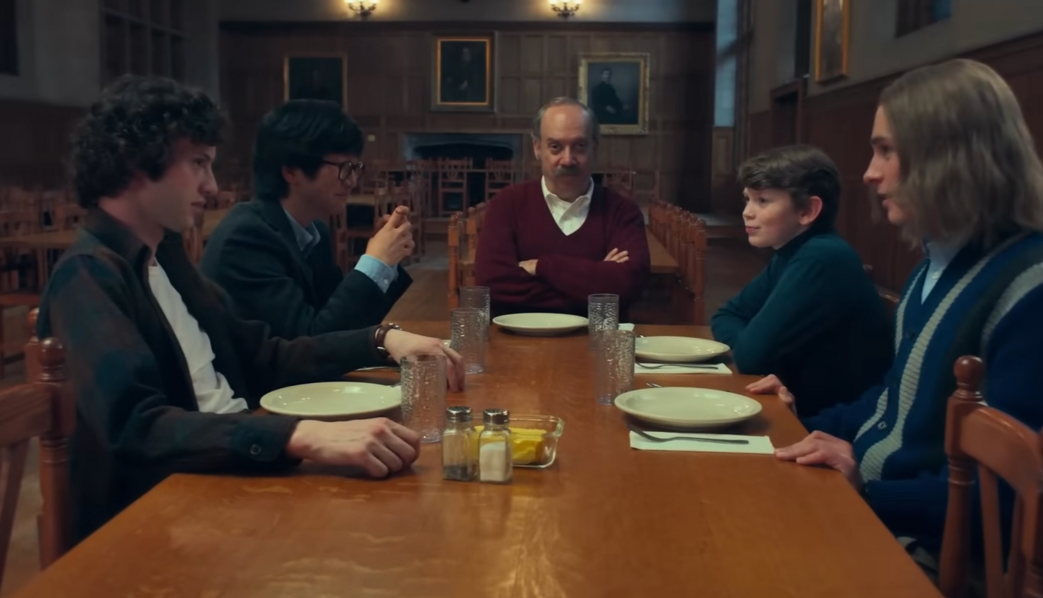 Paul Giamatti sits with a table of students at the dining hall in the movie The Holdovers.