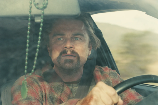 Leonardo DiCaprio looks in his rearview mirror looking panicked in the film One Battle After Another.