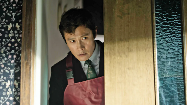 Lee Byung-hun peaks around a door in the film No Other Choice.
